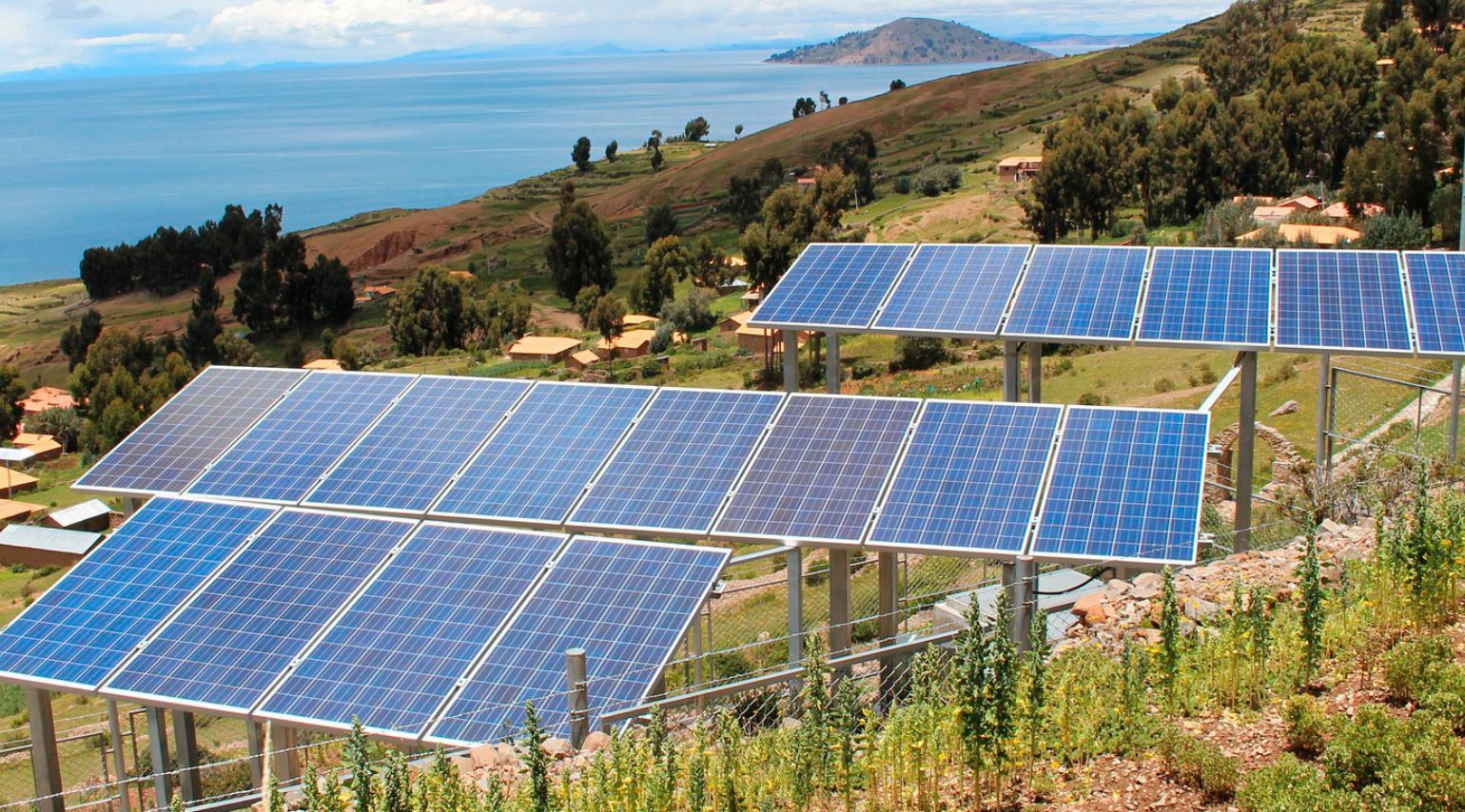 Many solar panels next to a large body of water